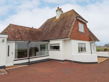 An exterior view of a house with white walls and a reddish-brown tiled roof at Whitestacks in Bamburgh