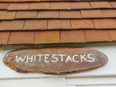 A wooden sign with the word Whitestacks under a tiled roof at Whitestacks Bamburgh