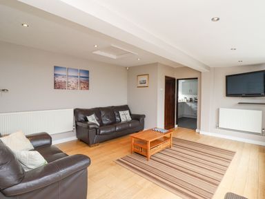 A living room with two leather sofas a wooden coffee table and a wall mounted television at Whitestacks in Bamburgh