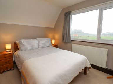 A bedroom with a double bed two bedside tables with lamps a window and a radiator at Whitestacks in Bamburgh