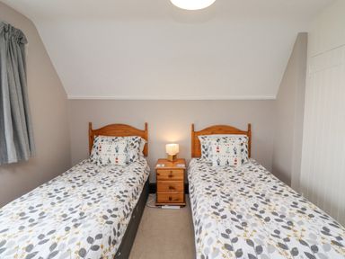 A bedroom with two single beds and a nightstand with a lamp at Whitestacks in Bamburgh
