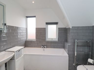 A bathroom with a bathtub sink storage cabinet and towel rack at Whitestacks in Bamburgh