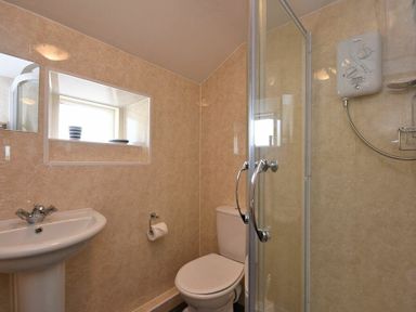 A bathroom with a pedestal sink toilet shower and small window at Bilton Farm Cottage No1 in Alnmouth