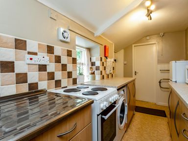 A kitchen with a stove washing machine counters and tiled backsplash at Bilton Farm Cottage No1 in Alnmouth
