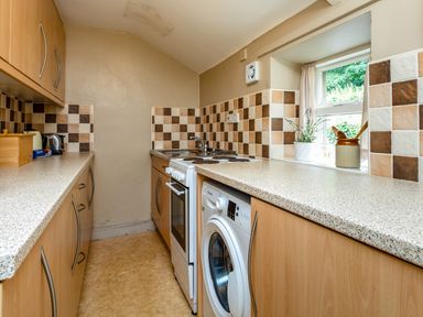 A kitchen with a washing machine stove sink and window at Bilton Farm Cottage No1 in Alnmouth