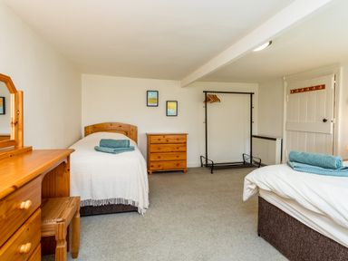 A bedroom with two single beds each with folded towels a wooden dresser and a wooden chest of drawers at Bilton Farm Cottage No1 in Alnmouth