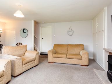 A living room with two beige sofas a fireplace built in cupboards a wall clock and a heart decoration at Bilton Farm Cottage No2 in Alnmouth