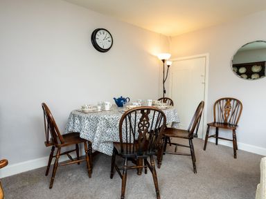 A dining room with a table set for tea and wooden chairs at Bilton Farm Cottage No2 in Alnmouth