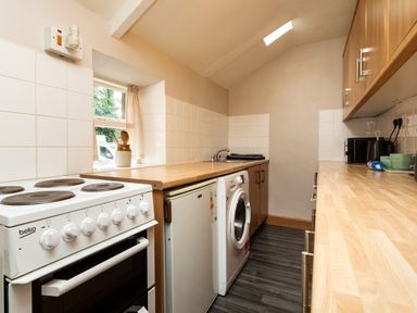 A kitchen with an electric stove washing machine mini fridge microwave and wooden countertops at Bilton Farm Cottage No2 in Alnmouth