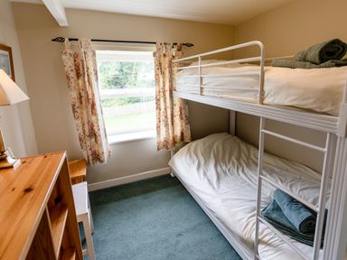 A small bedroom with bunk beds and floral curtains at Bilton Farm Cottage No2 in Alnmouth