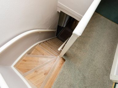 A staircase with wooden steps and white handrails leading down from carpeted landing at Bilton Farm Cottage No2 in Alnmouth