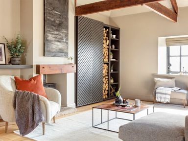 A living room with a cream armchair with cushion and throw a wood storage unit and a wooden coffee table with decorative items at Lantern View in Eglingham