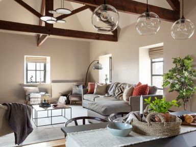 A living room with a gray sofa pillows and plants on a table at Lantern View in Eglingham