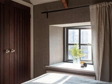 A window with a vase and candle on the sill next to a wooden door in a bedroom at Lantern View in Eglingham