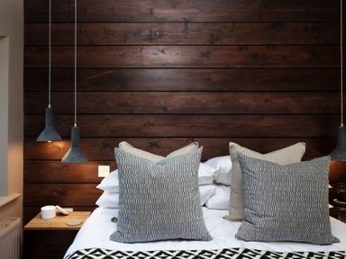 A bedroom with a bed with large pillows and a wooden headboard at Lantern View in Eglingham