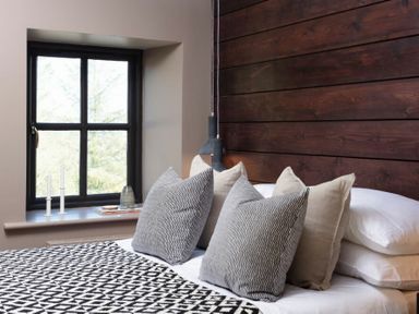 A bedroom with a bed with pillows and a patterned blanket next to a window at Lantern View in Eglingham