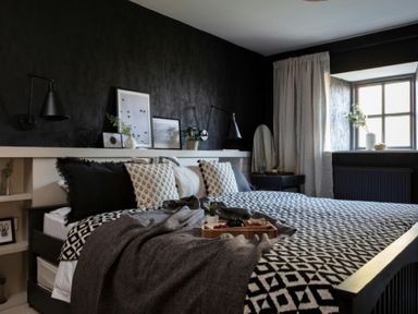 A bedroom with a bed with patterned bedding a window with curtains and framed pictures on a shelf at Lantern View in Eglingham