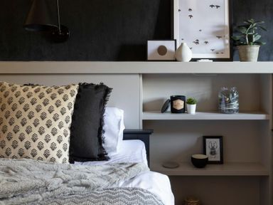 A bedroom with patterned pillows on a bed and shelves with decorations at Lantern View in Eglingham