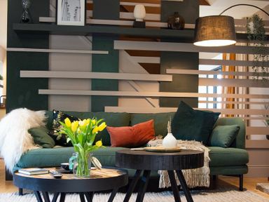 A living room with a green sofa yellow flowers on a coffee table and a hanging lamp at The Bolthole in Eglingham