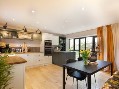 A kitchen with a black dining table and chairs next to large windows with curtains at The Bolthole in Eglingham