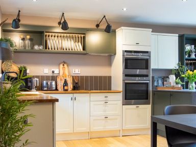 A kitchen with white cabinets wooden countertops built in double oven and dining table with chairs at The Bolthole in Eglingham