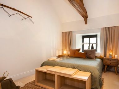 A bedroom with a bed pillows bedside tables window and a wooden storage bench at The Bolthole in Eglingham