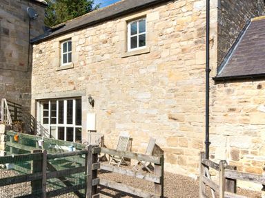 An outdoor area with wooden chairs wooden fencing and stone walls at The Bolthole in Eglingham