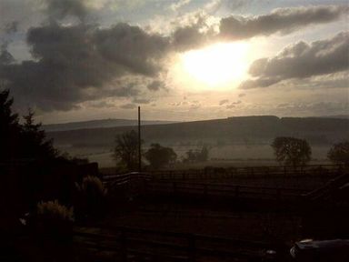 A rural landscape with trees and fences under a cloudy sky at sunrise at The Bolthole in Eglingham