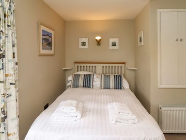 A bedroom with a double bed with striped pillows and folded towels on top at Strandline in Alnmouth