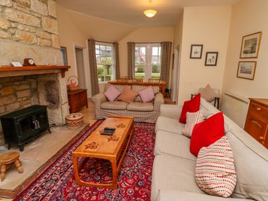 A living room with sofas a wooden coffee table and a stone fireplace at Armstrong Cottages No2 in Bamburgh
