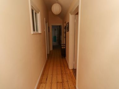 A narrow hallway with wooden floorboards and beige walls at Armstrong Cottages No2 in Bamburgh