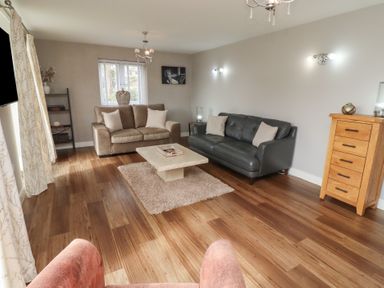 A living room with two sofas a coffee table and wooden chest of drawers at Assisi Apartment in Alnmouth