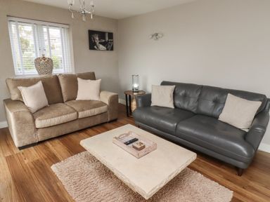 A living room with two sofas a coffee table and a window at Assisi Apartment in Alnmouth