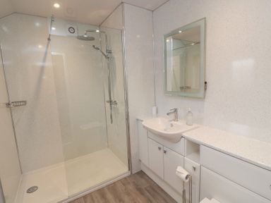 A bathroom with a walk-in shower sink countertop and mirror at Beach View in Seahouses