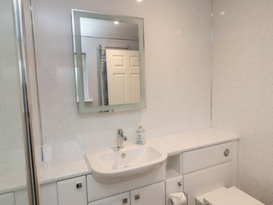 A bathroom with a sink countertop mirror and a toilet at Beach View in Seahouses