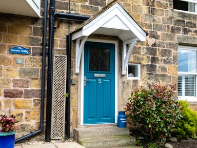A blue front door with the number 5 on a stone house with plants outside at Begonia House in Alnmouth