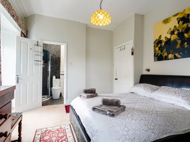 A bedroom with a bed and folded towels two doors and a dresser with a chair at Begonia House in Alnmouth