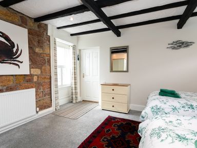 A bedroom with twin beds a chest of drawers a mirror and a window at Begonia House in Alnmouth