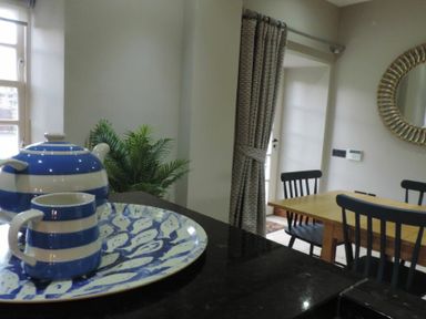 A kitchen counter with a blue and white teapot and mug on a decorative tray with a dining table and chairs in the background at Budle Granary Bamburgh