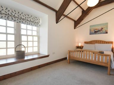 A bedroom with a wooden bed and beams on the ceiling at Budle Granary in Bamburgh