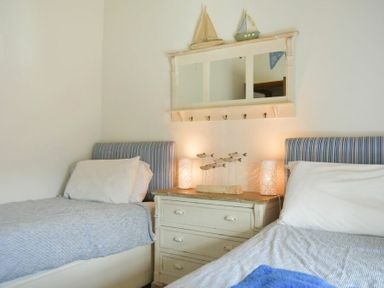 A bedroom with two single beds a chest of drawers with lamps and nautical decorations at Budle Granary in Bamburgh
