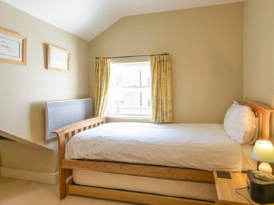 A bedroom with a single bed a wooden nightstand lamp and two framed pictures on the wall at Cheshill Cottage in Alnmouth