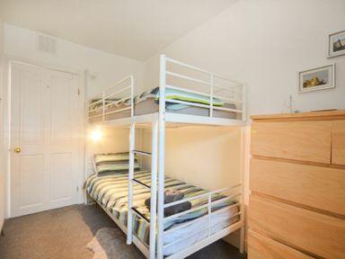 A bedroom with a white bunk bed and wooden dresser at Crier Cottage Alnwick