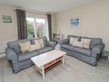 A living room with two grey sofas and a white coffee table at Curlew Cottage in Seahouses