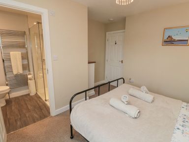 A bedroom with a bed and rolled towels near an ensuite bathroom at Curlew Cottage in Seahouses