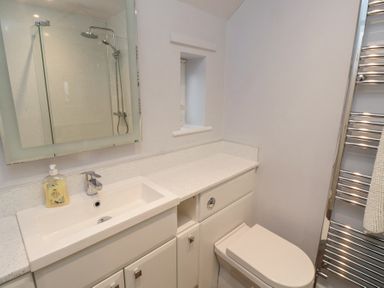 A bathroom with a sink countertop toilet mirror and shower at Curlew Cottage in Seahouses