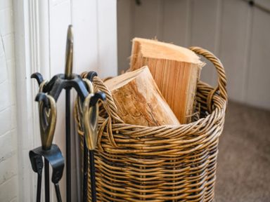 A basket with logs beside fireplace tools at Elliot Cottage in Bamburgh