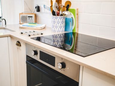 A kitchen countertop with a stovetop oven and utensils in a holder at Elliot Cottage in Bamburgh