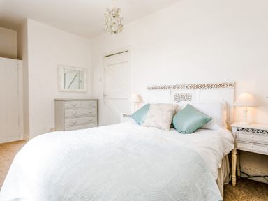 A bedroom with a double bed with pillows and nightstands with lamps at Elliot Cottage in Bamburgh