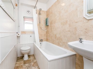 A bathroom with a bathtub shower toilet and sink at Elliot Cottage in Bamburgh